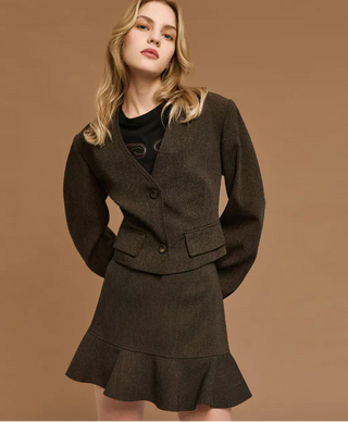 Woman wearing a brown suit with a black top against a brown background